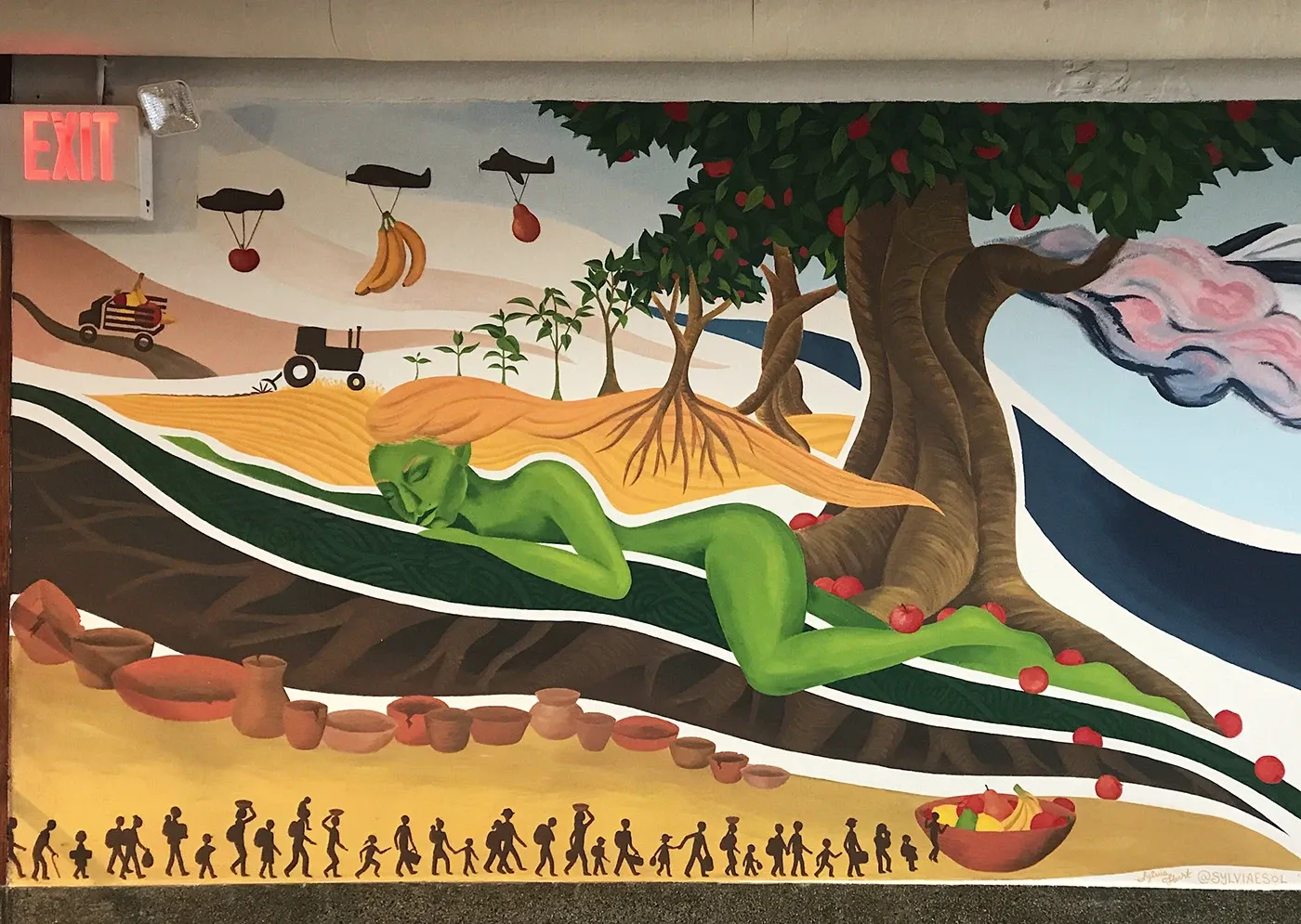 Pachamama mural: a reclining green earth-goddess figure beneath a fruit-bearing tree, with tilled fields, clay vessels, and a procession of silhouetted figures.