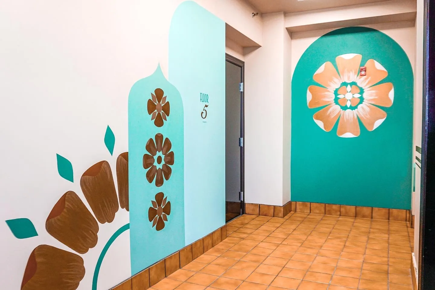 Tall interior mural in blue, purple, and metallic gold geometric forms with a Floor 4 marker.