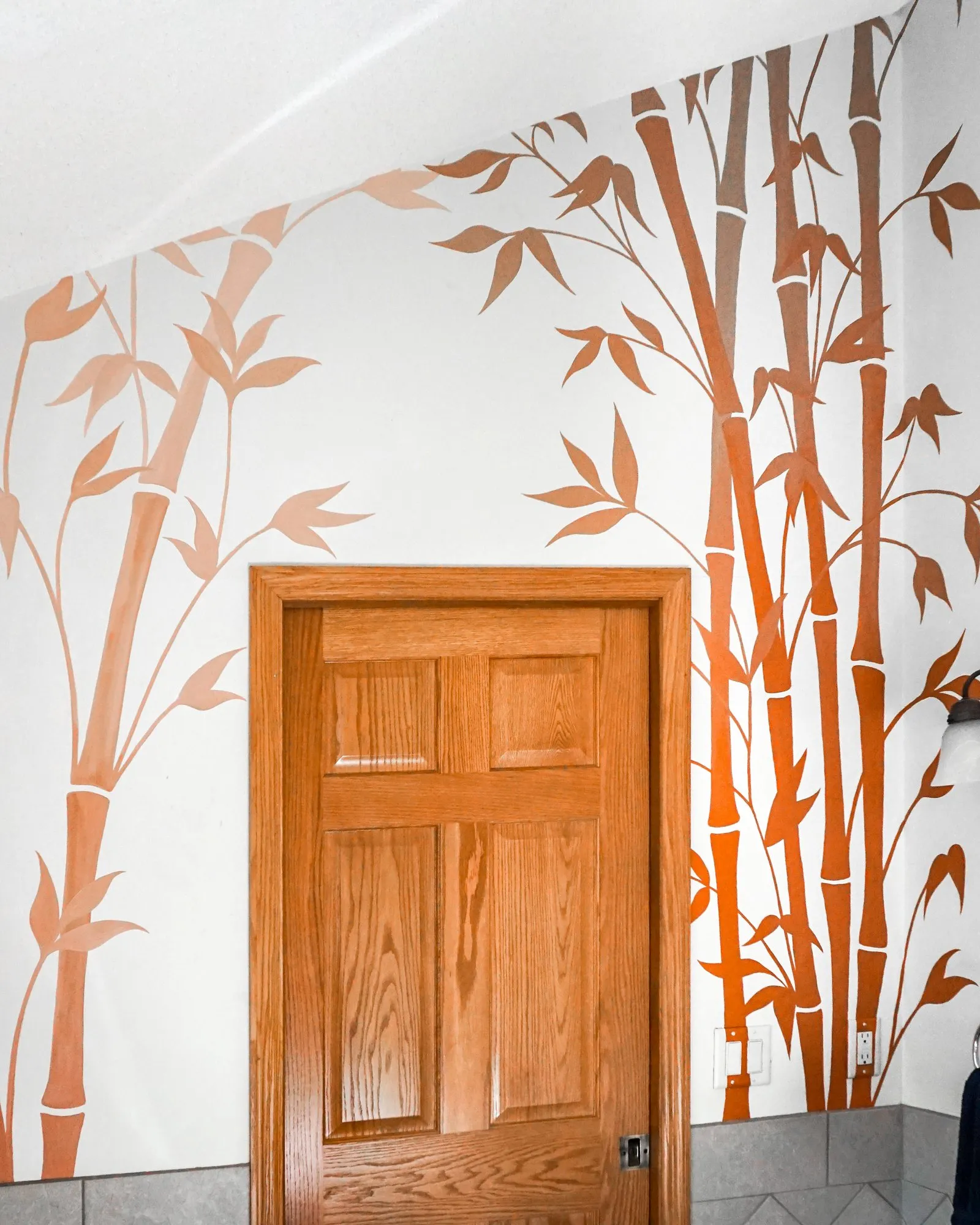 Copper and orange bamboo mural framing a doorway in the bathroom.