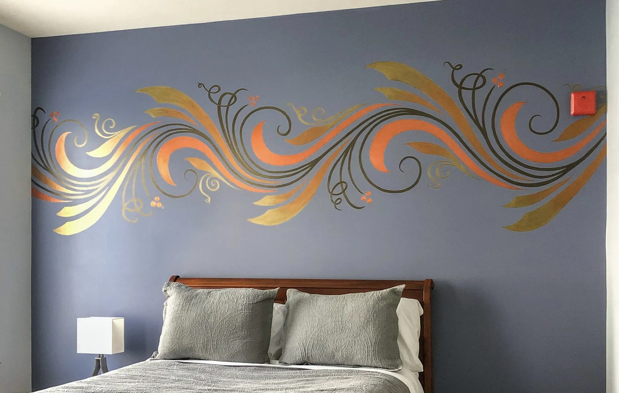 Metallic line-work mural flowing above a bed in copper and gold.