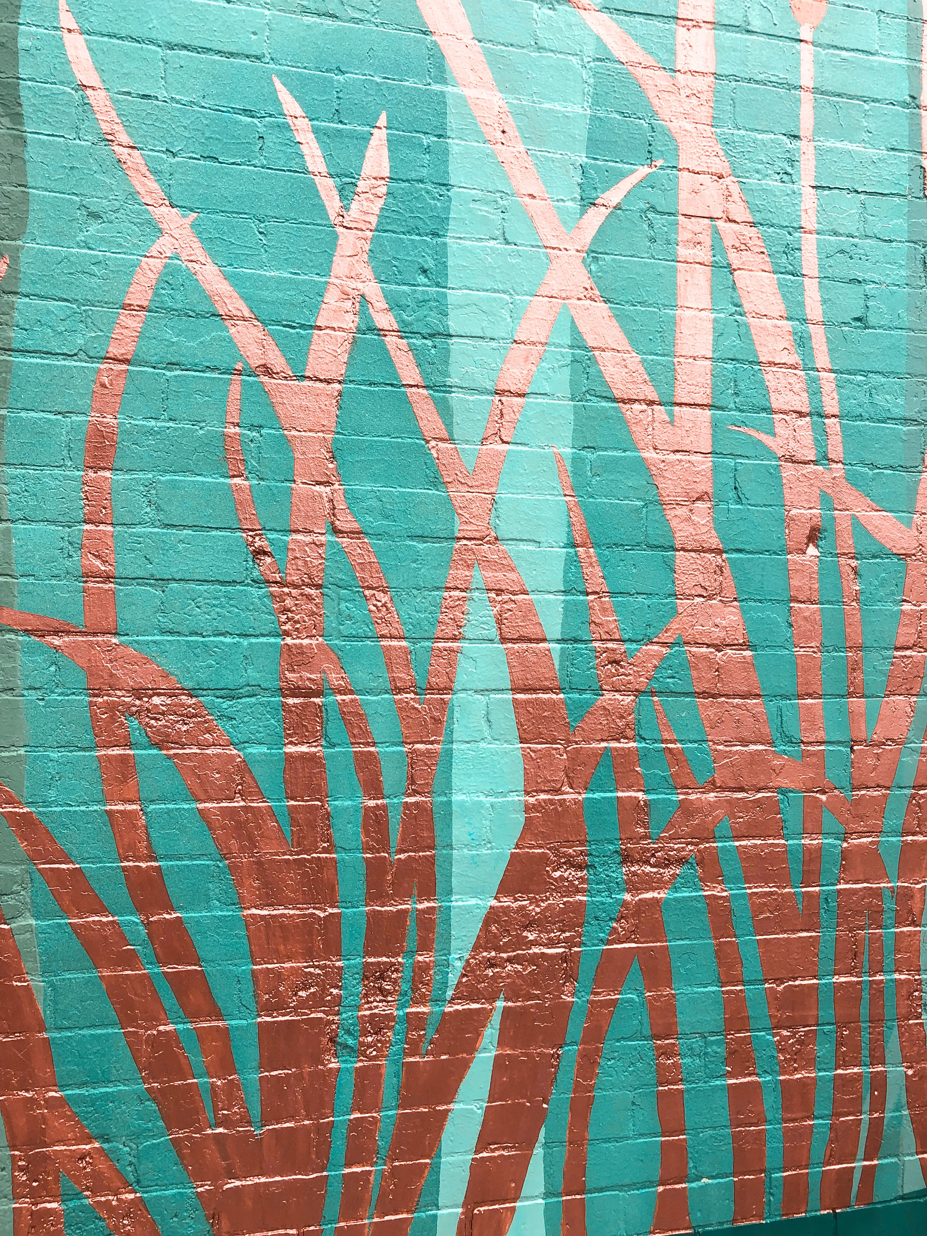 Close detail of the mural’s copper reeds against teal brick.