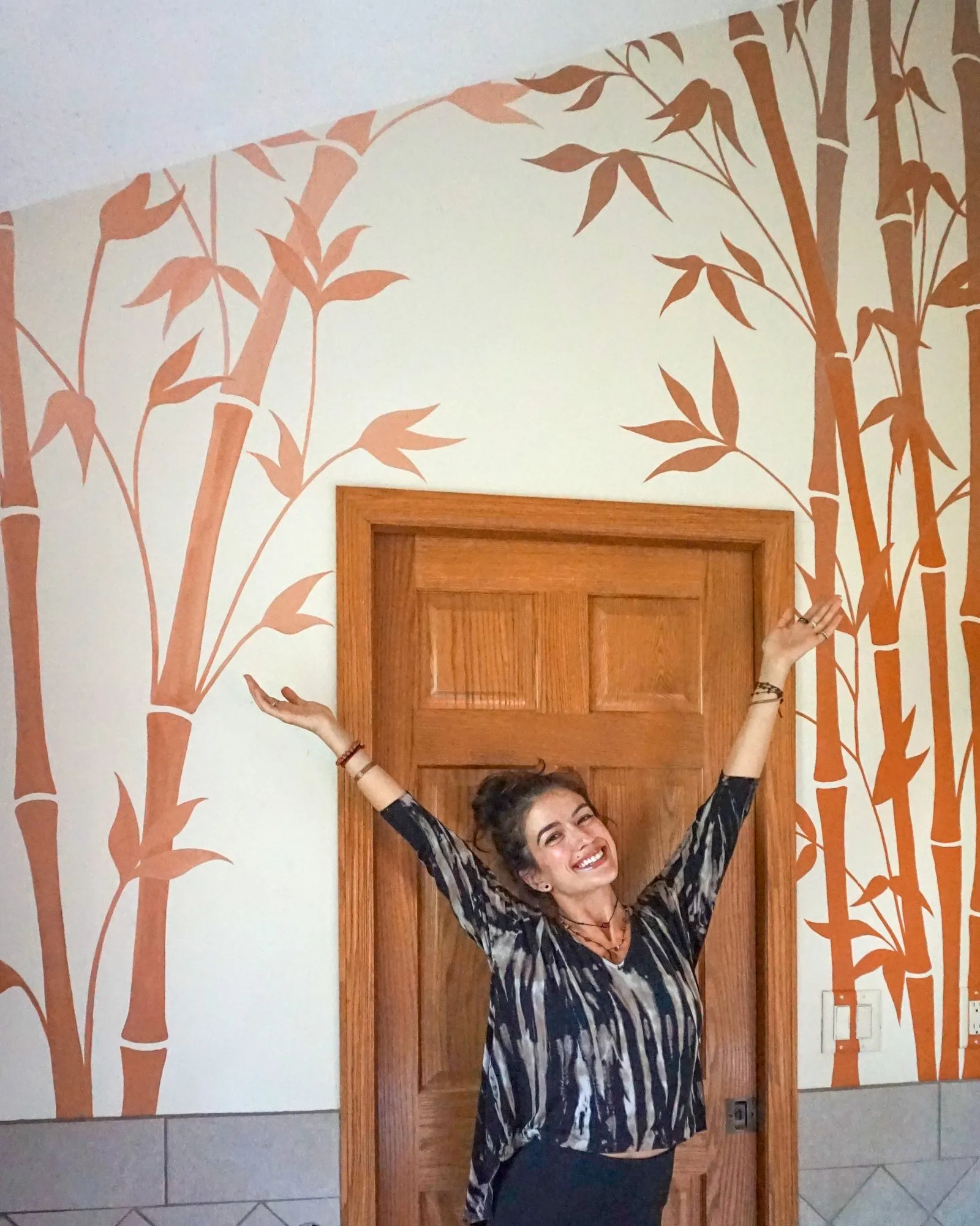 The artist standing before the finished bamboo bathroom mural.