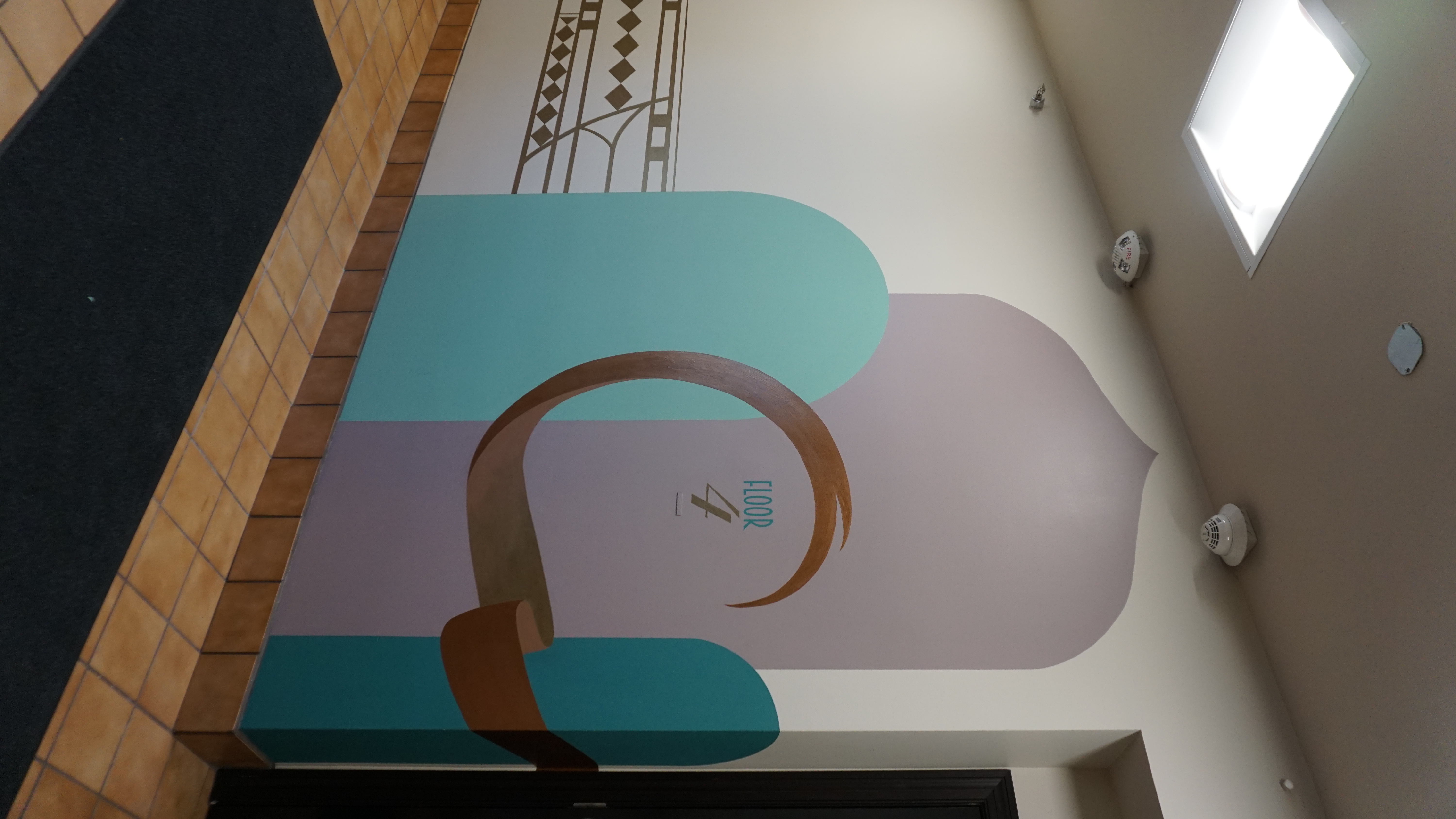 Tall interior mural in teal, blush, and metallic gold geometric forms with a Floor 4 marker.