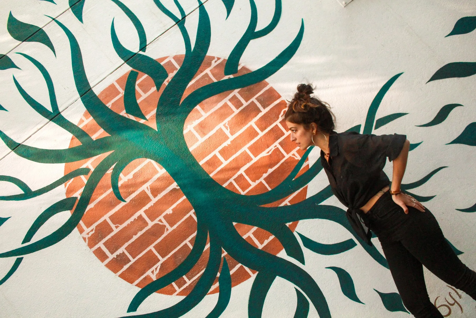 Close view of the tree-of-life mural with the artist beside it.