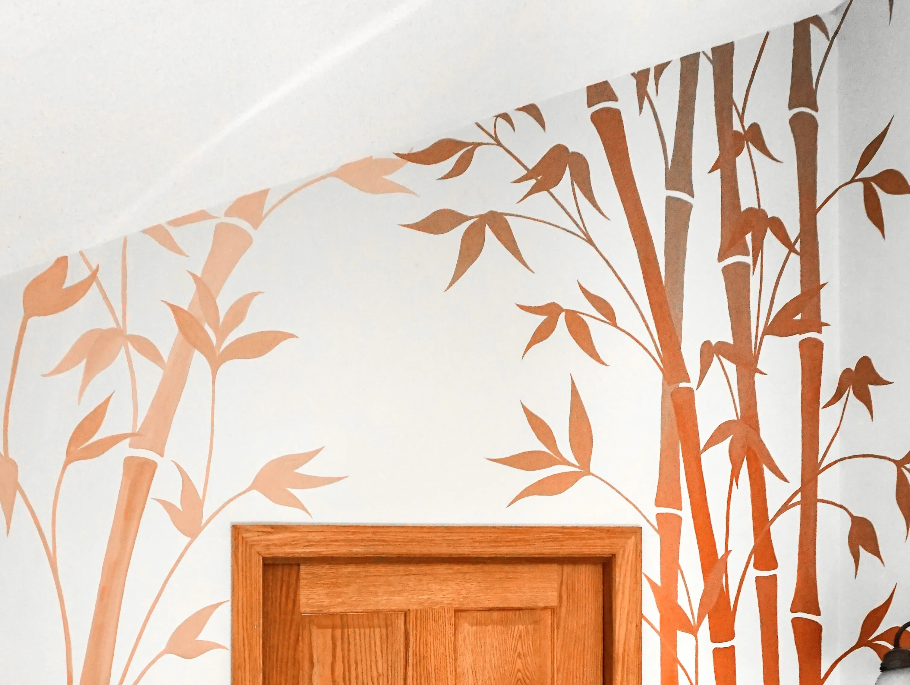 Bathroom mural of a copper moon and birds in flight over white bamboo, wrapping the wall above a corner tub.